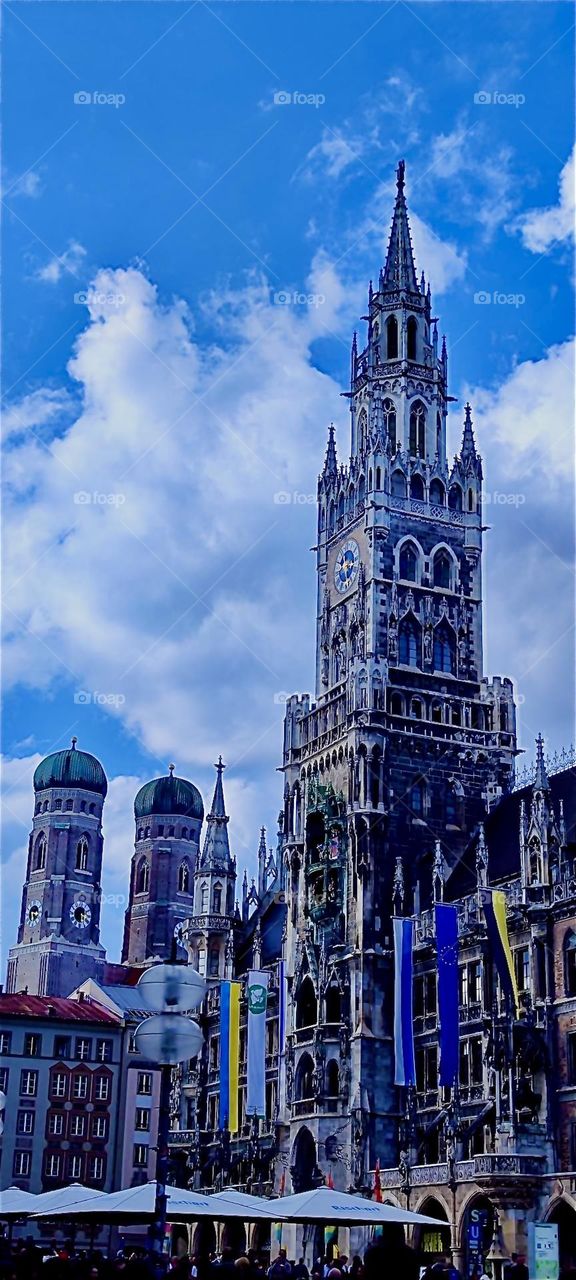 This is “Marienplatz” or “St Mary Our Lady’s Square” in “Munich”, capitol of “Bavaria”. What looks like a gothic cathedral is the “New City Hall”. The two smaller towers are of the “Frauenkirche”, “Our Lady’s Church”. 2024. Hypnotic Productions