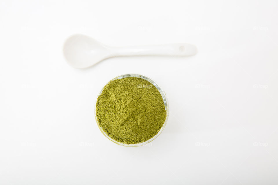 Green! Minimalist image with green wheat grass powder in a white bowl with a white spoon flat lay