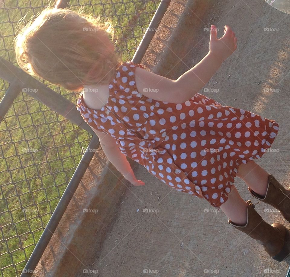 Beauty in boots. Little girl in dress and boots at baseball fields