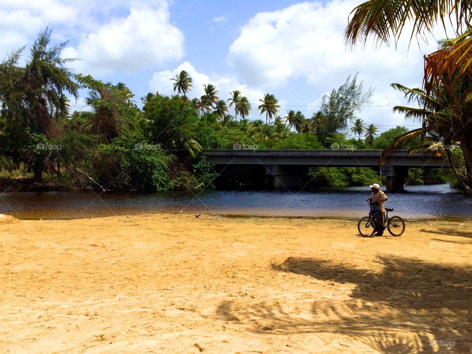 Going Fishing. A fisherman in his way to the beach passing a river estuary in Puerto Rico.