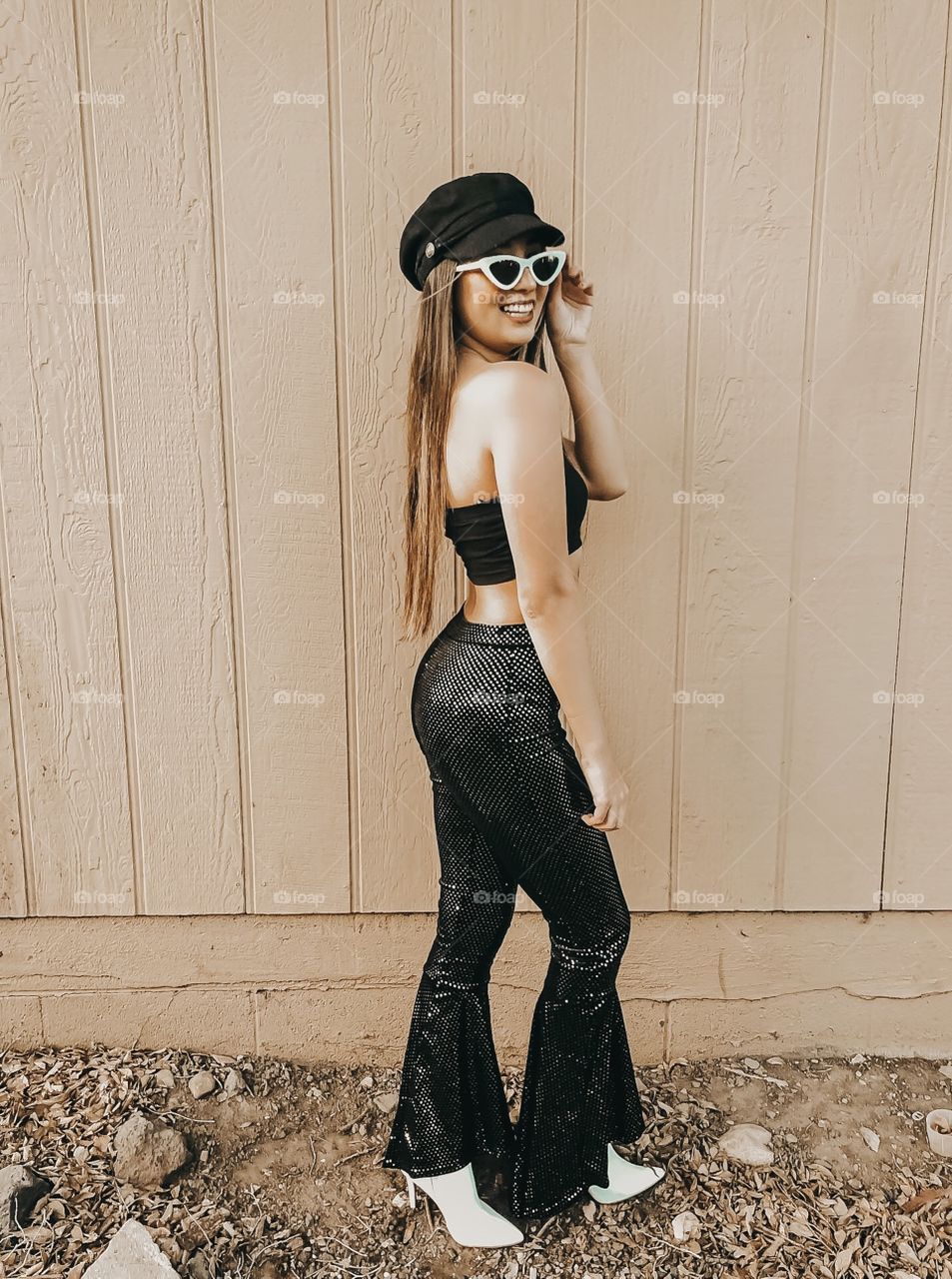 Young girl dressed up in sequin flare pants with fun white sunglasses.