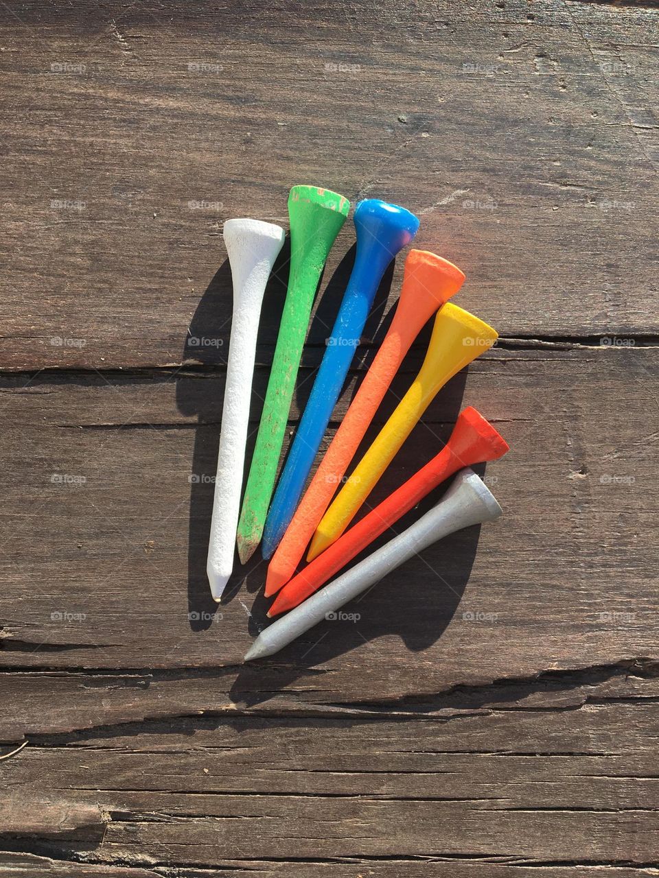 Colorful wooden tees on wood backside 