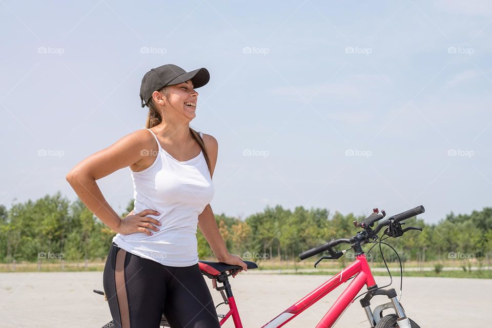 woman in sports clothes and cap riding her bicycle