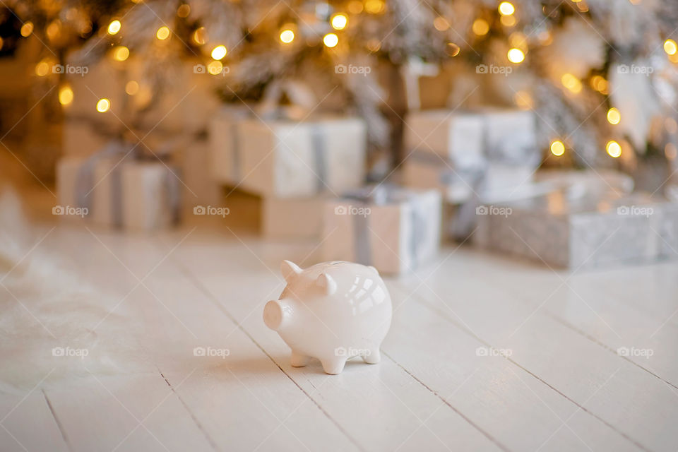 piggy bank with 100 dollars banknote in festive New Year atmosphere of scenery.  Magical bokeh with Christmas tree and bright lights.