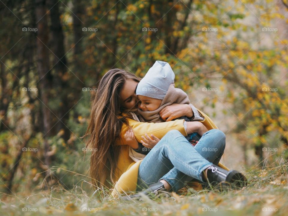 Young beautiful mom with her little son in autumn forest 