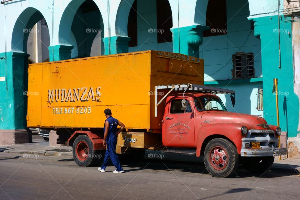 Old American truck parked in the street in front of colorful building representing classical architecture of Havana, Cuba on December 26, 2013.