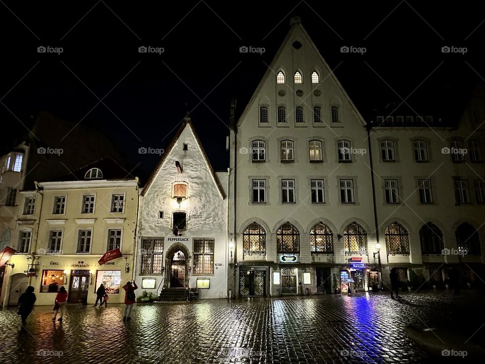 illuminated houses with triangular roofs, reflection on wet asphalt, darkness