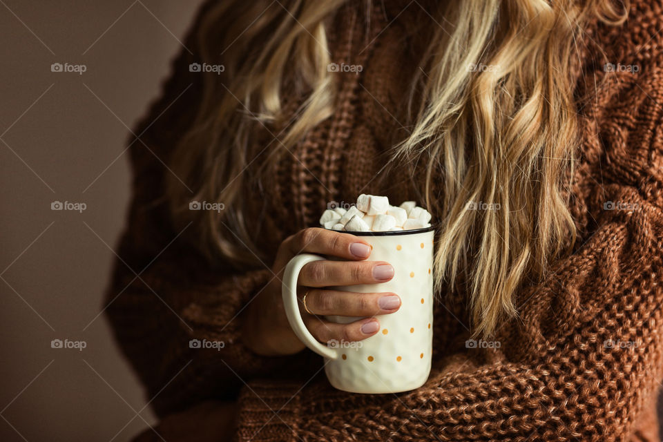 Woman hand holding cup of coffee with marshmallow 