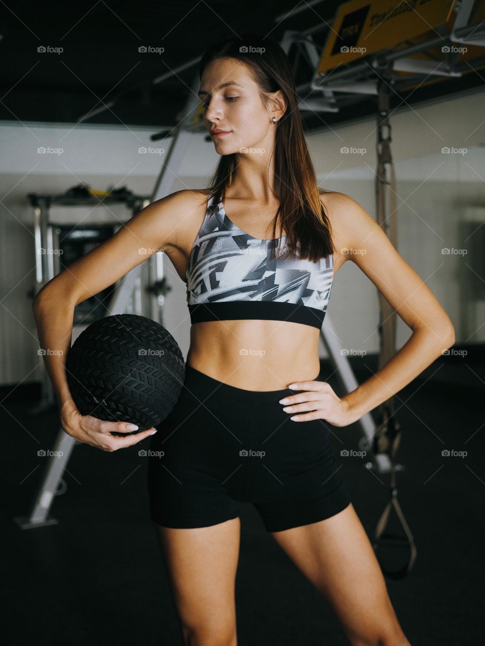 Young beautiful woman holding ball in gym 