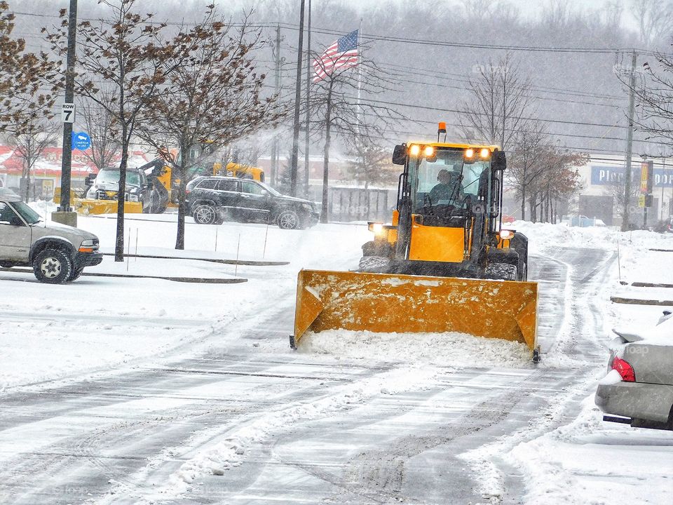 It’s snowing! Yellow parking lot snow plow...