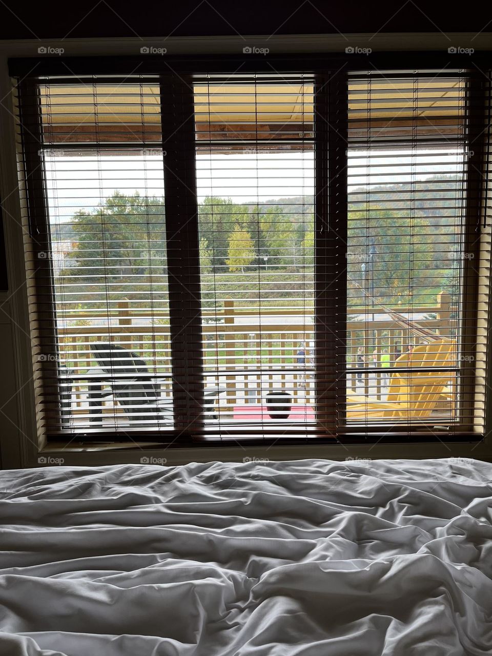 Mountain view (blue mountain, collingwood, Ontario) from bed through window. Balcony with coloured muskoka chairs in Autumn 