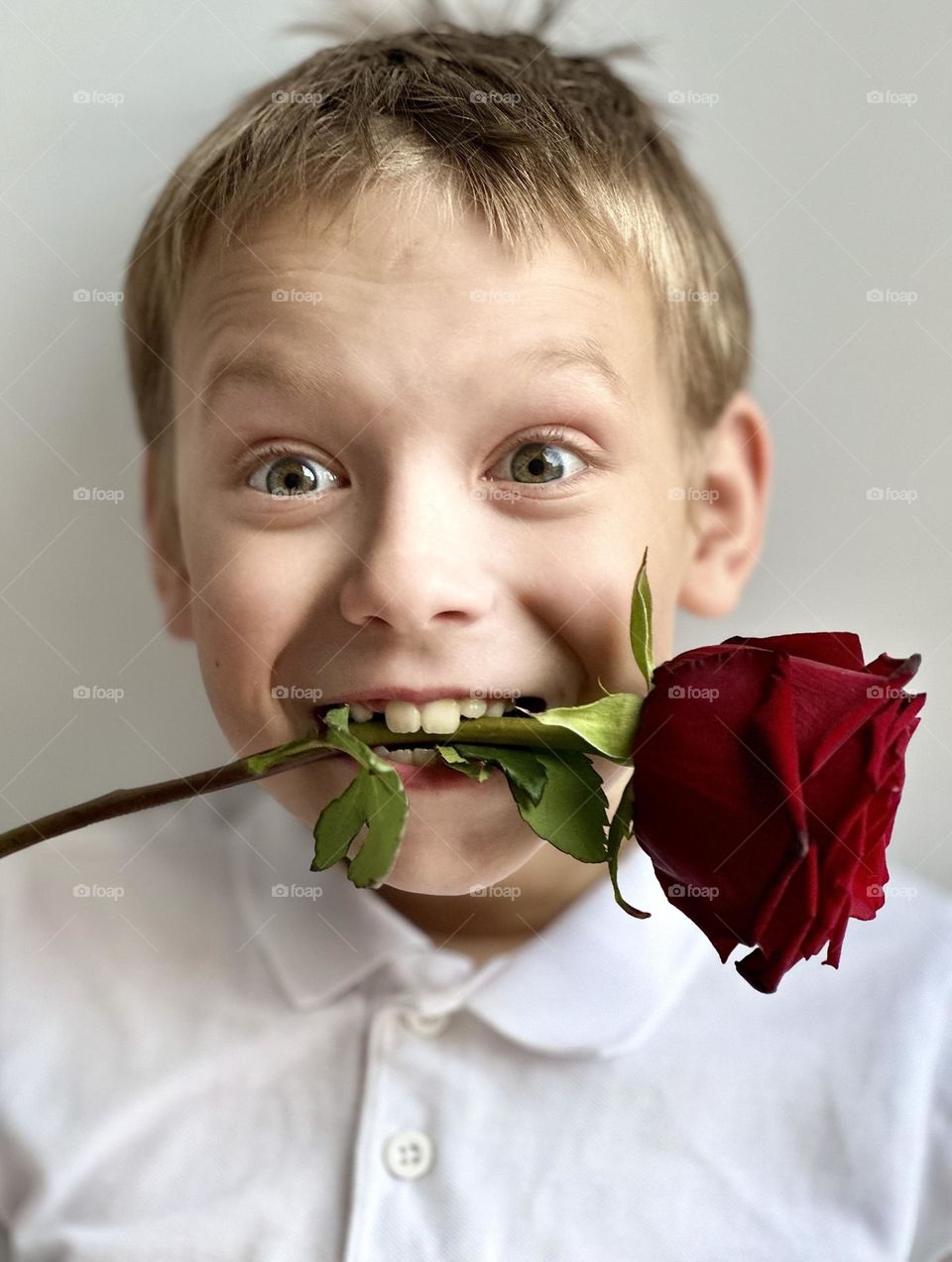 smiling boy with a rose in his mouth