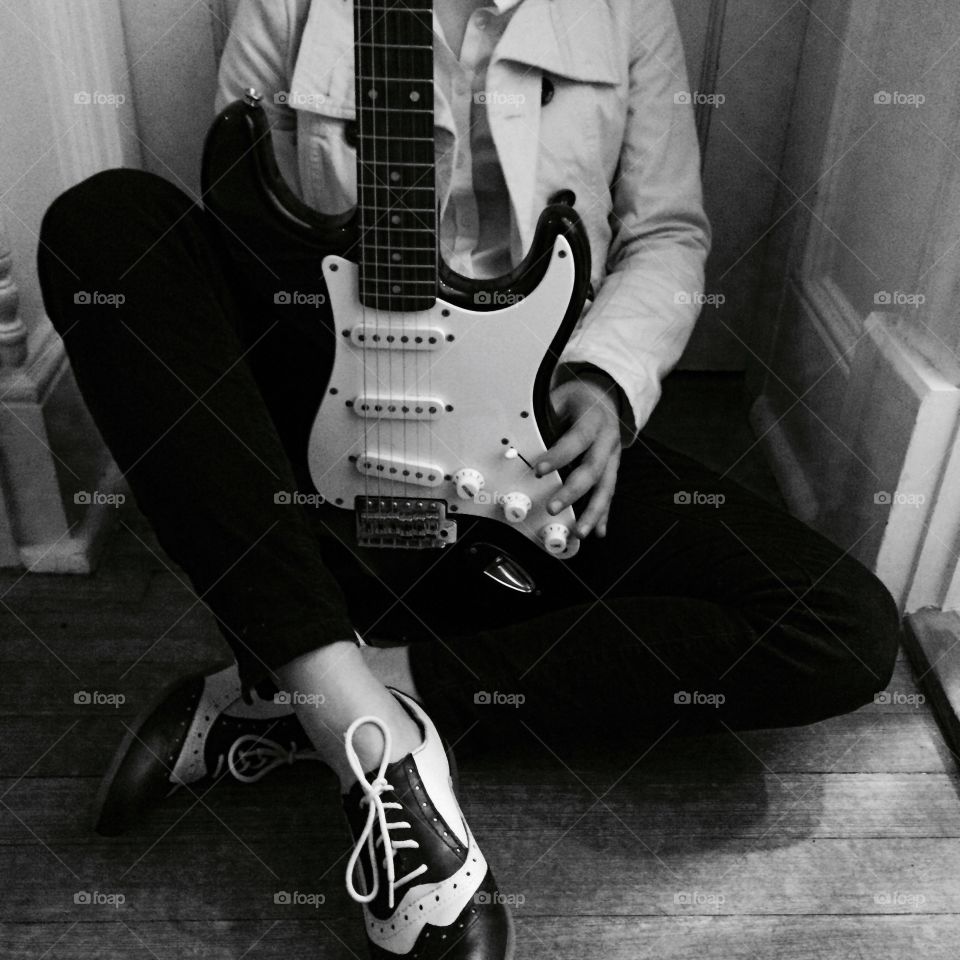 A girl poses before a guitar performance with her black Squier Stratocaster and her Børn oxford wingtips