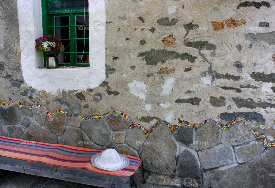 An old house facade, bench, window, white hat, stones