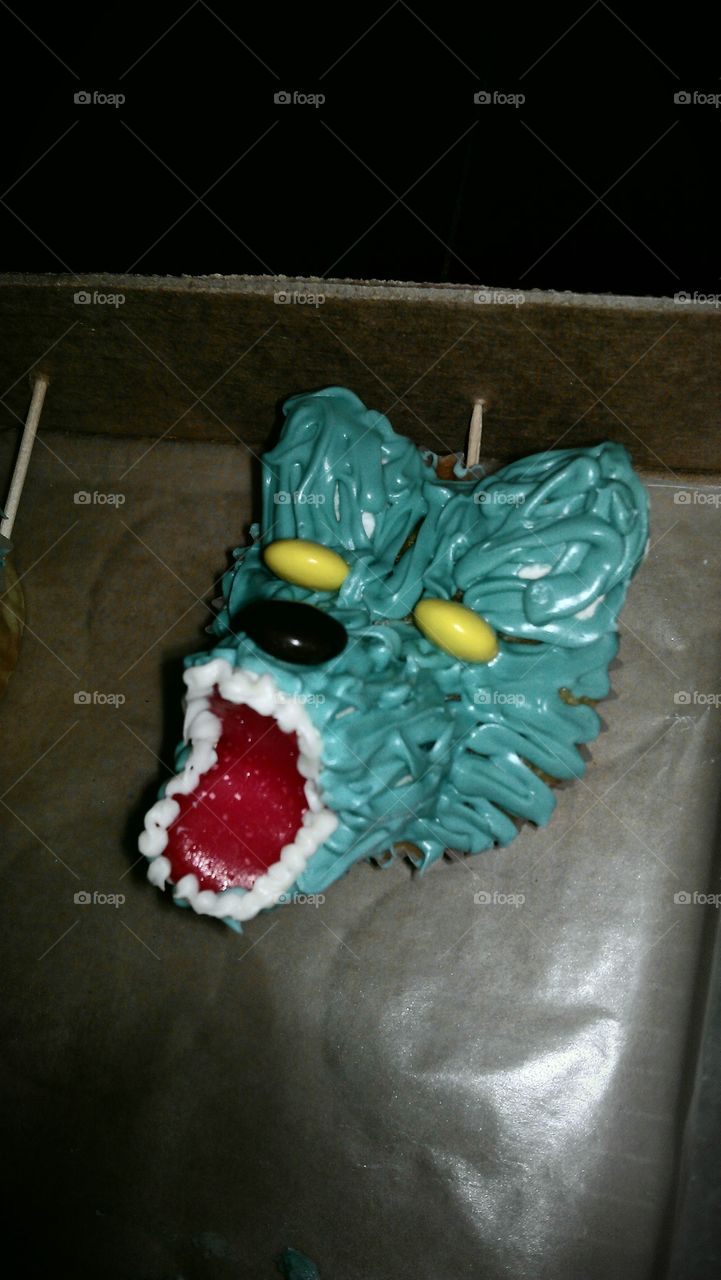 wolf cupcake topped with marshmallow, candy, fruit strips, and icing
