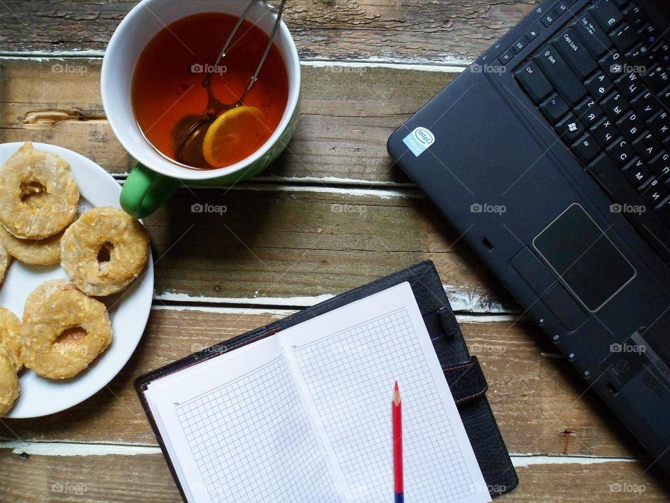 cup of tea, cakes laptop notebook on the table