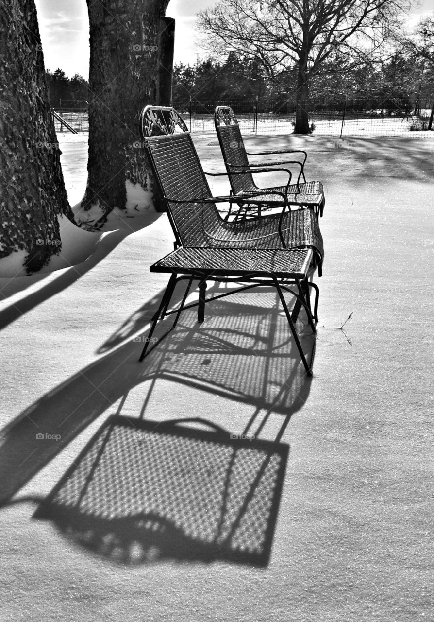 Patio furniture in the snow casting a shadow