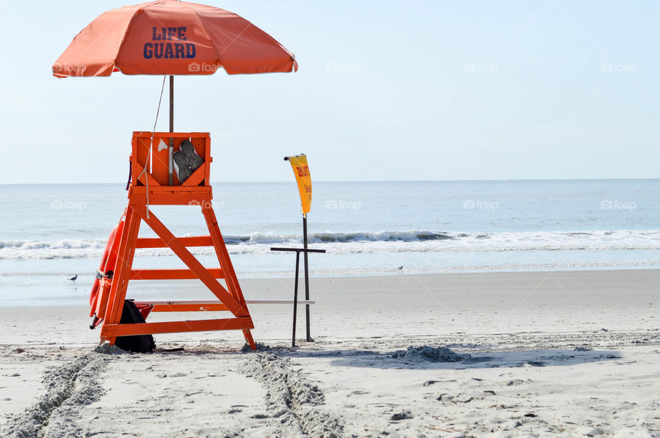 Empty lifeguard chair and umbrella on the beach with no people