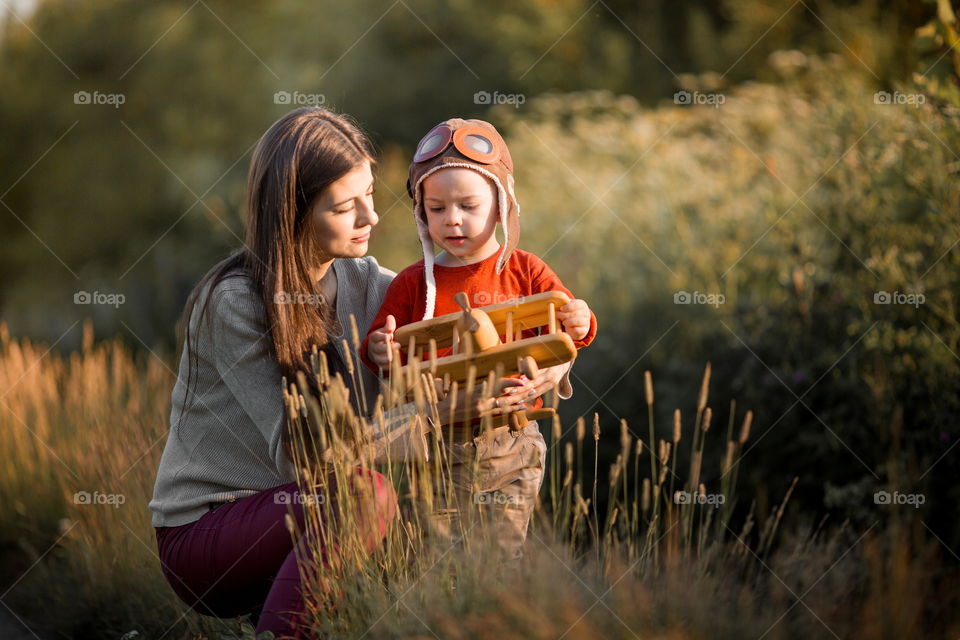 Mother and son with wooden plane at sunset