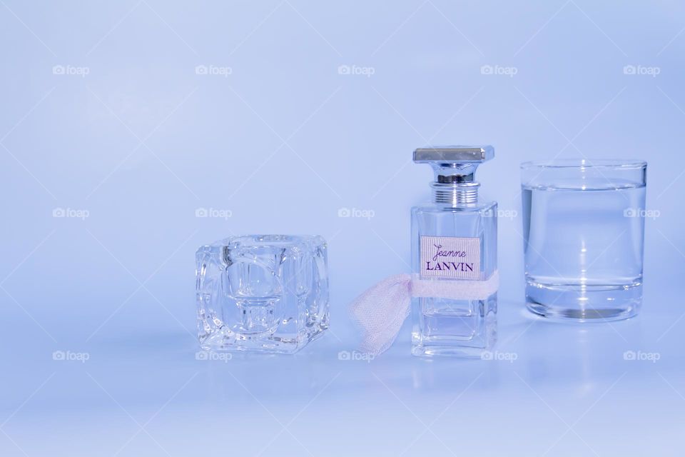 Eau de Parfum Lanvin pink on a blue background and a glass of clean, clear water.