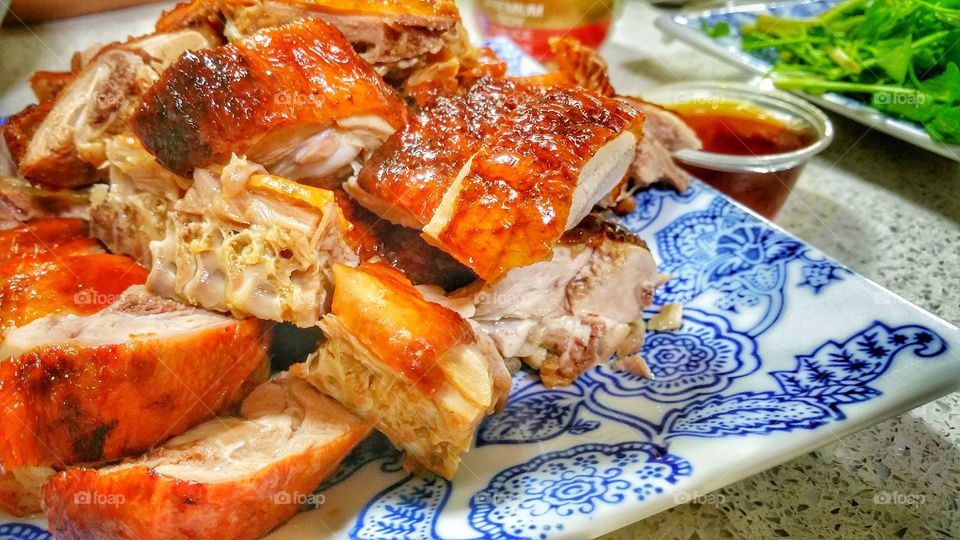 Cantonese roast duck, presented on a plate in pieces, accompanied by a small tub of plum sauce. The duck has a shinning red-brownish skin frequently seen hanging behind shop windows.