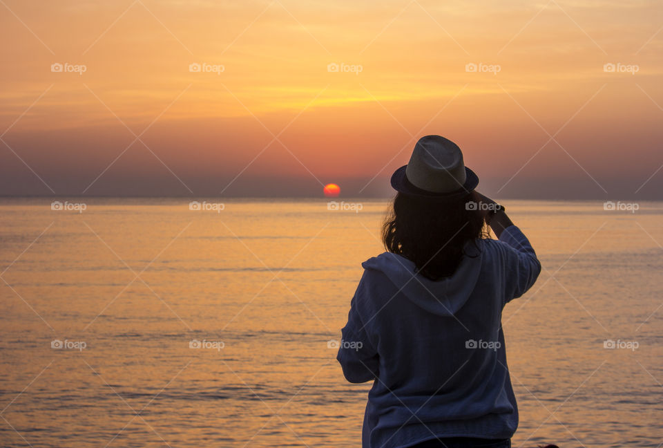 Woman looking at sunrise over the sea, beautiful nature