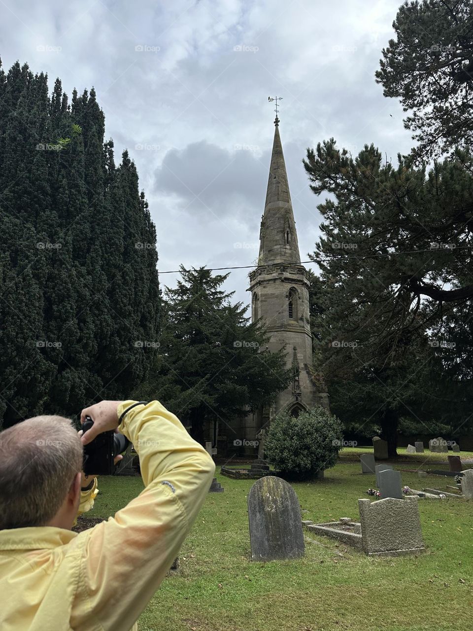 Father photographing Ansty church in England on canal narrowboat holiday vacation Father’s Day summer stormy weather