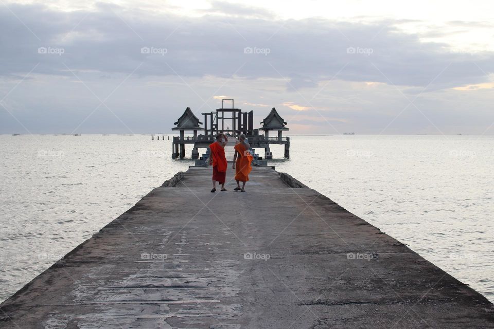 Thai Monks at a Pier by an abandoned Buddhist temple in Thailand Southeast Asia in the evening