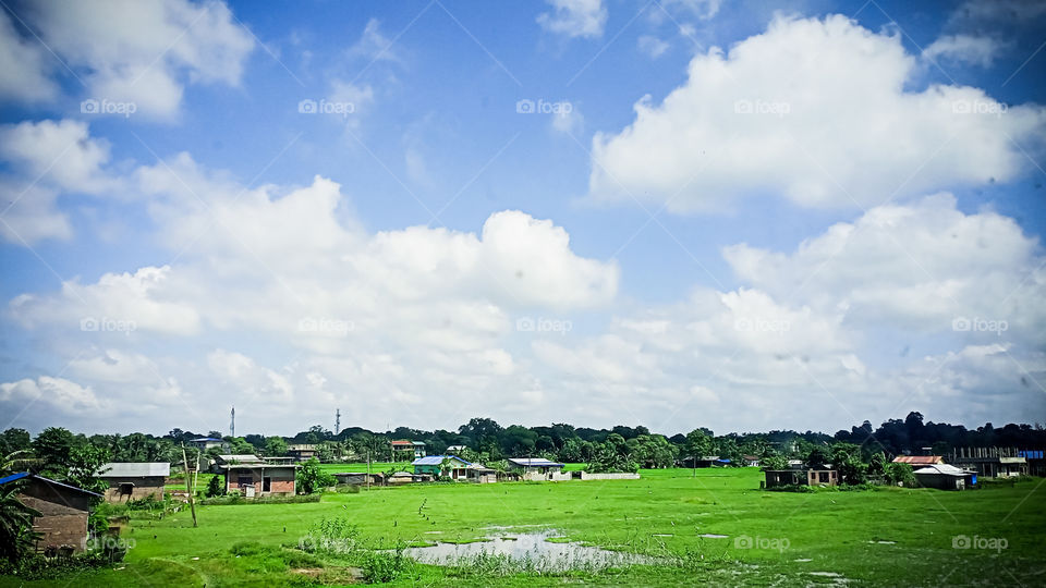 Photo of a village captured from the Highway while travelling. Village on the opposite side of the highway. village and along with the sky, blue sky also got captured during that moment ..