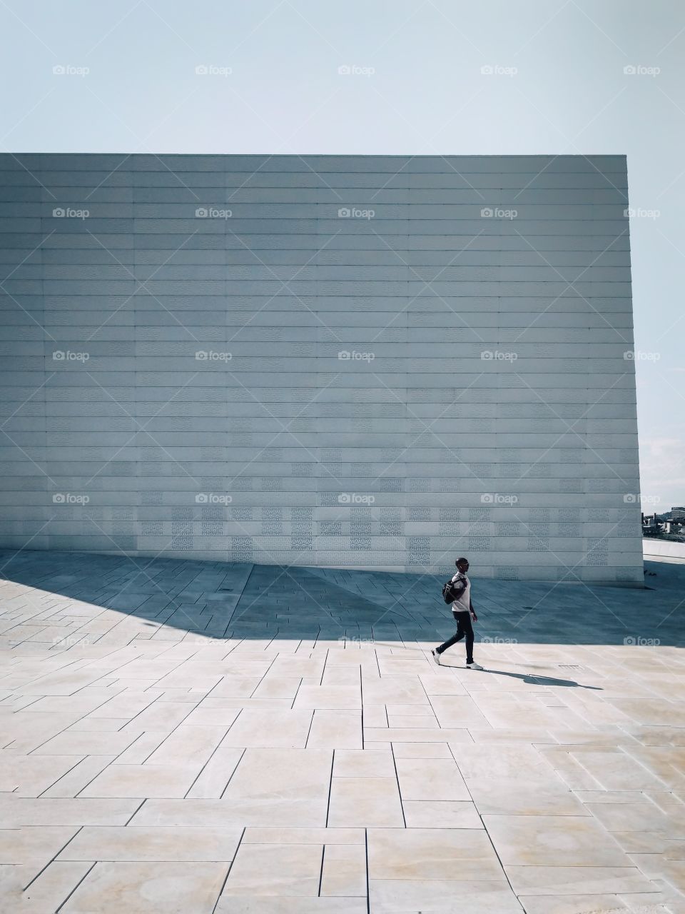 Young man walking outdoors with modern building in the background