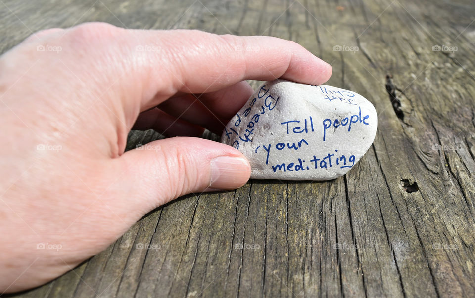 Hand holding a stone with an affirmation written on it