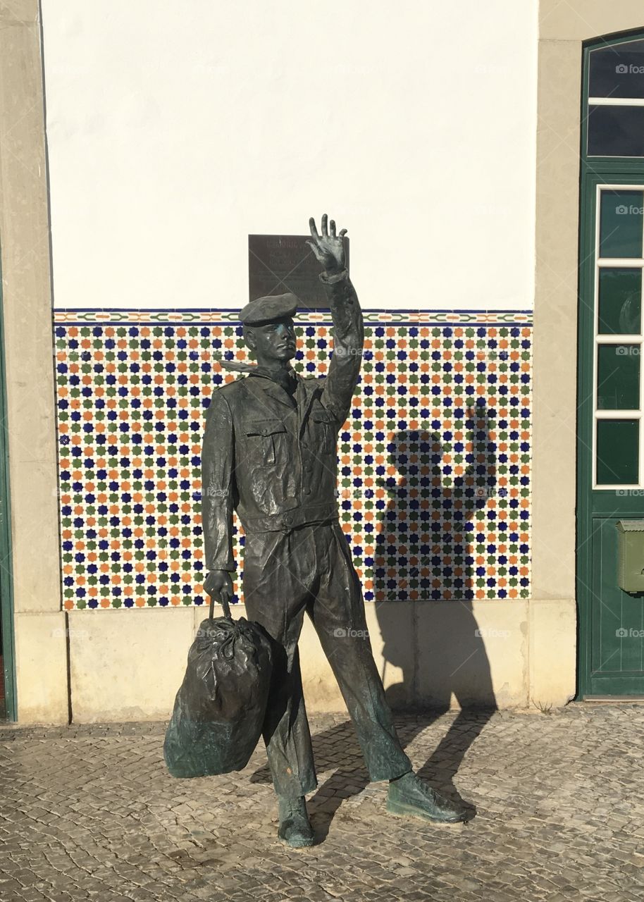 Traveler’s sculpture before a station with its shadow 