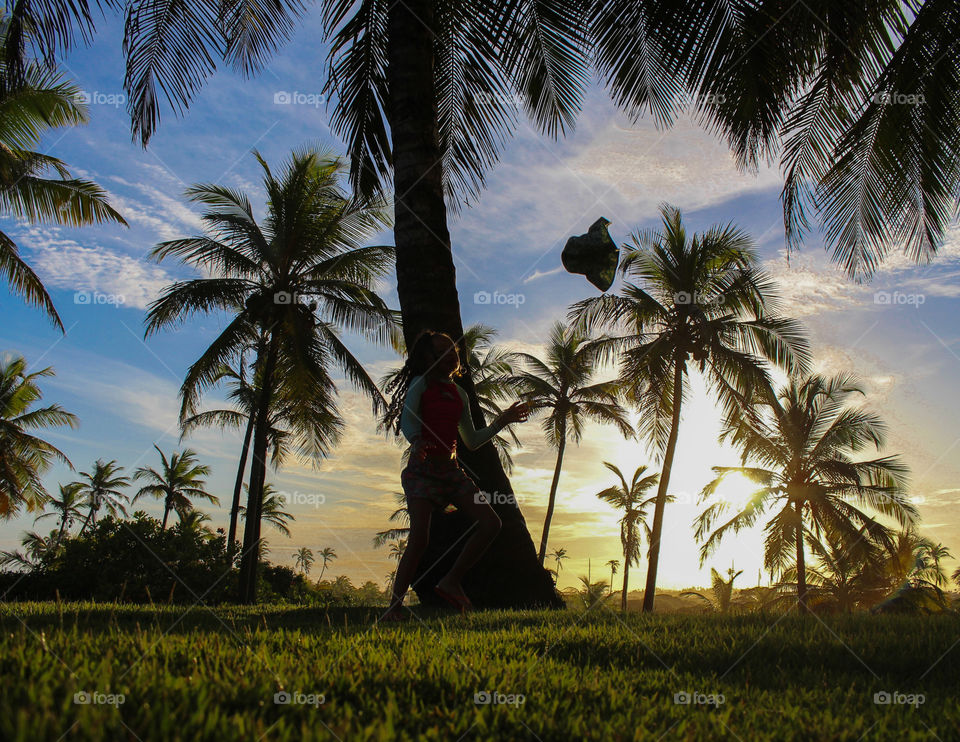 Little girl throwing hat up at sunset