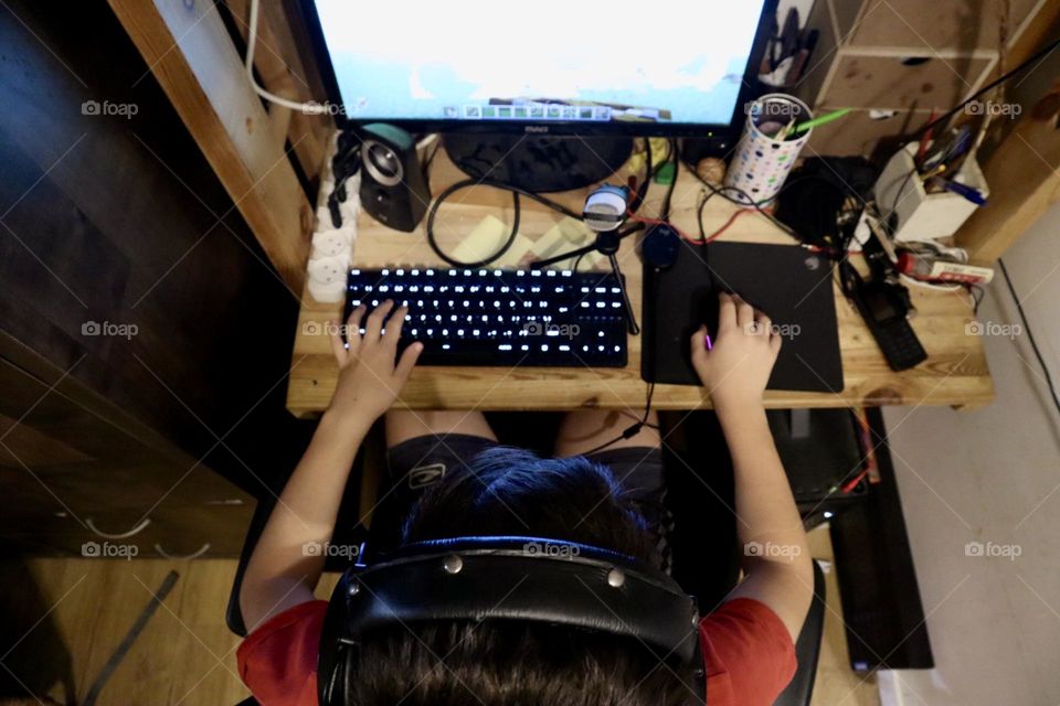 Kid playing video games in his computer upper view