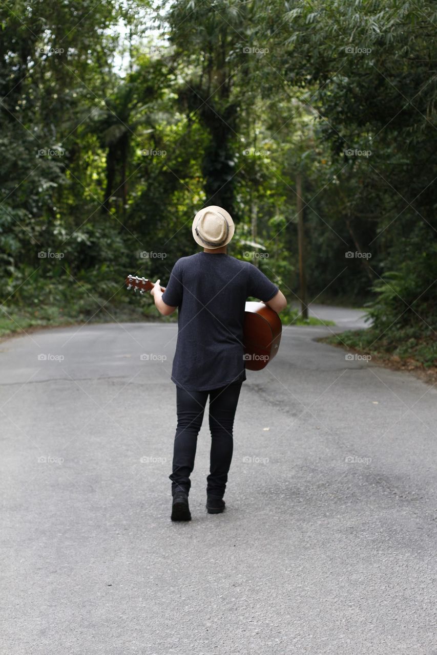 Boy playing guitar on the road 