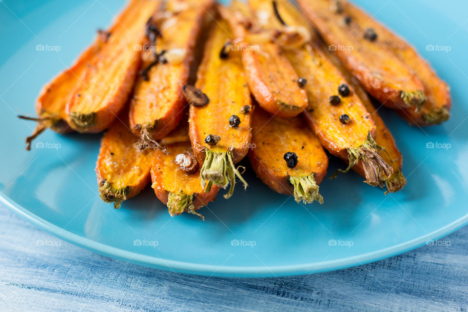 Baked carrots with spices on blue plate