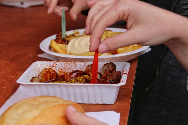Currywurst with fries and mayonnaise in a plastic plate