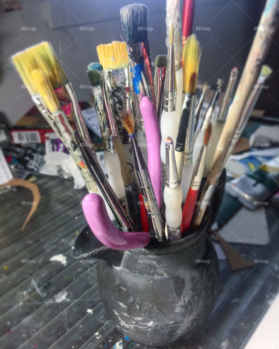 Collection of various size artist brushes in a old metal vessel 