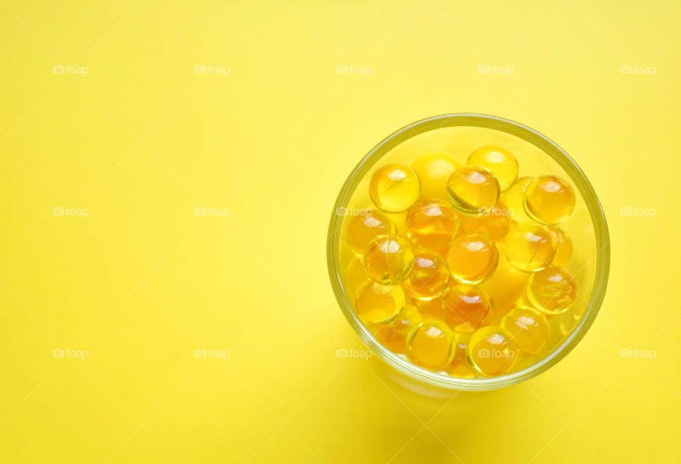 vitamin capsules oils round top view yellow background