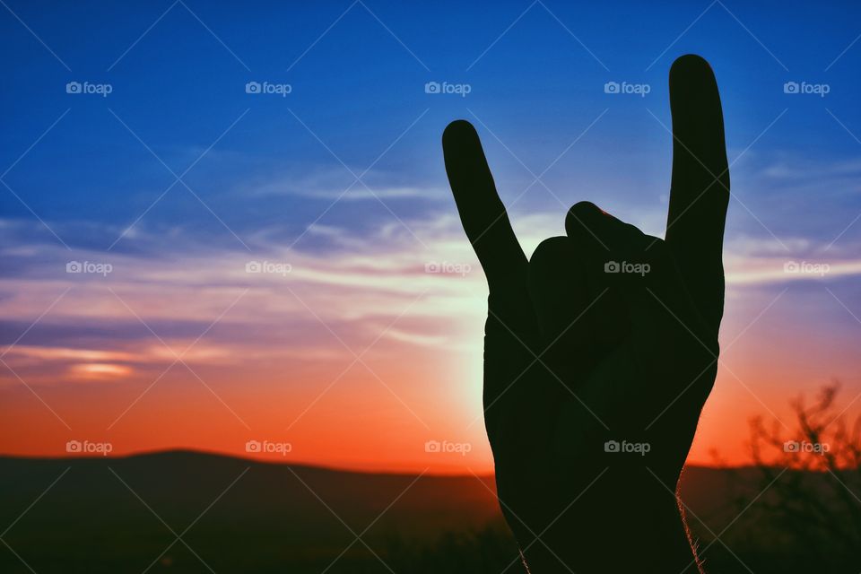 Rock hand sign in a beautiful, fading sunset