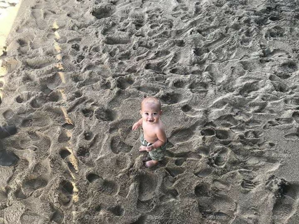 Baby  and footprints  on the sand.