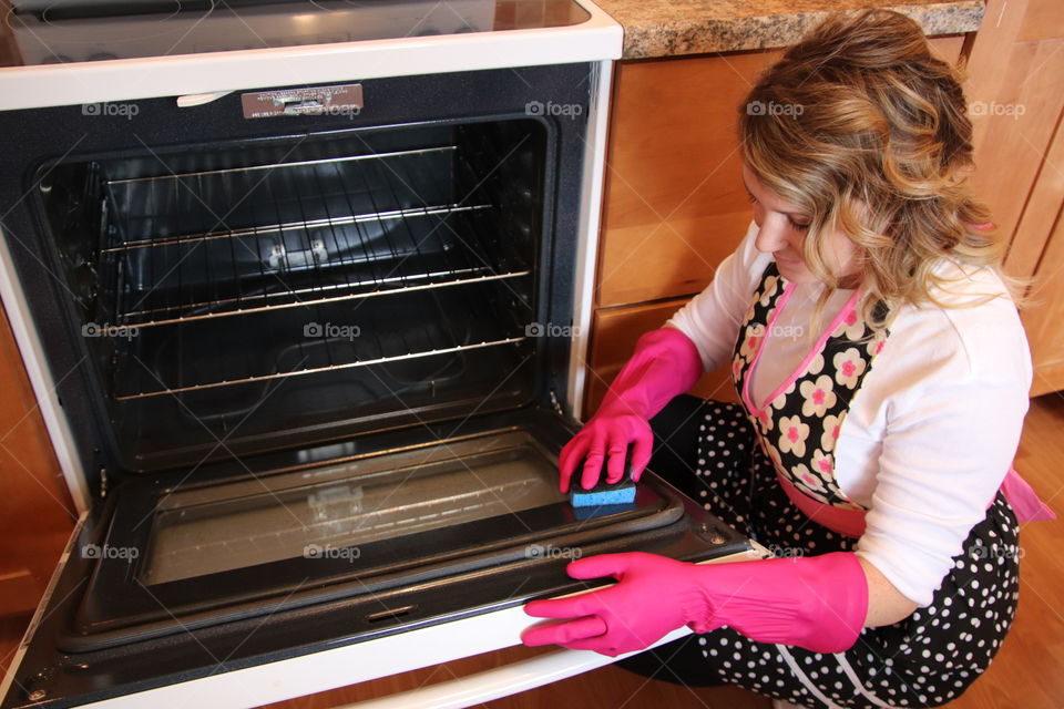 Woman cleaning oven wearing Playtex glove and using OCedar sponge 