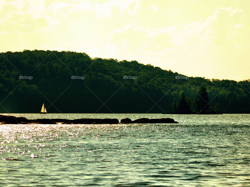 Sailing in the Adirondacks. Landscape shot of a sailboat on a lake in the adirondack mountains of upstate New York 