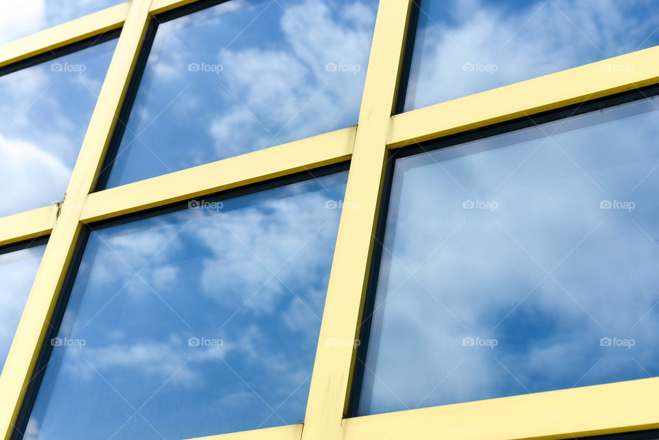 Close-up of square building windows with the reflection of the sky and clouds