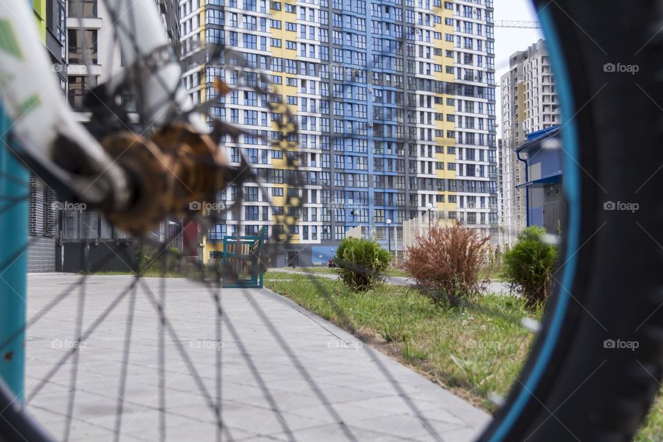 A modern city with its skyscraper yellow and blue houses through the wheel of a bicycle.