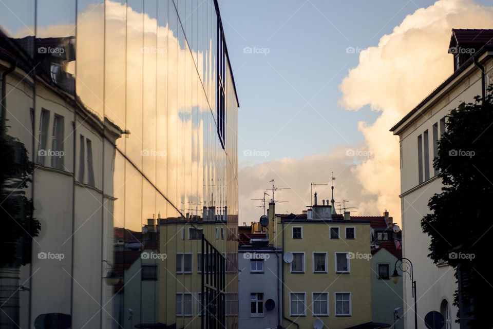Evening city view in Poland.  A large cloud is reflected in the glass facade of the building.