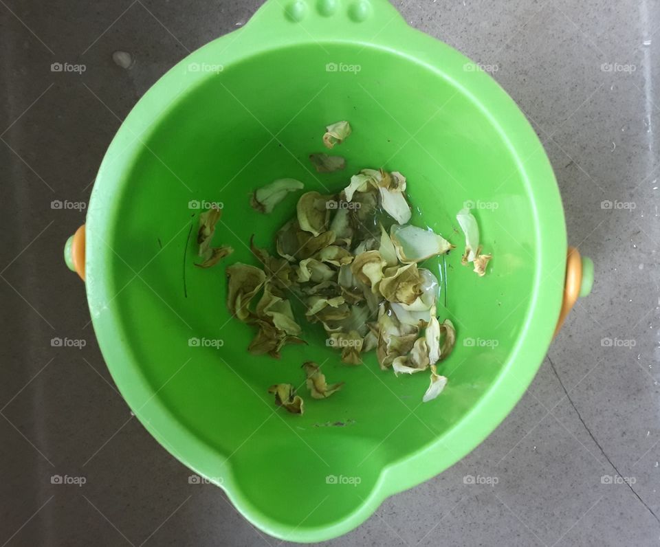 wilted rose petals in a green bucket