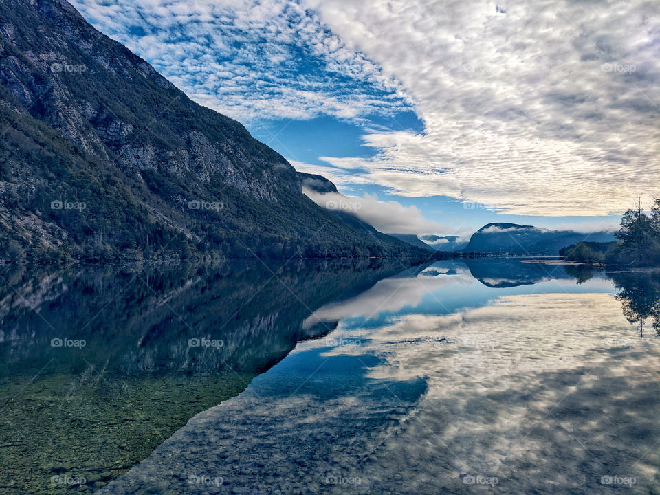 Scenic view of the beautiful reflection of the blue cloudy sky and Alps mountains in a lake in autumn trip in Slovenia.