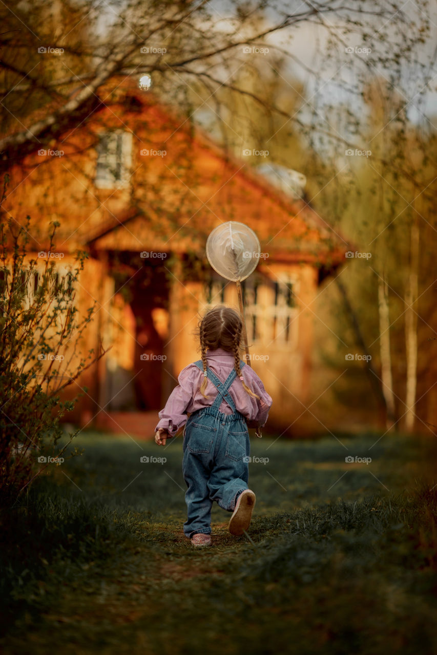 Little girl with butterfly net outdoor at sunset