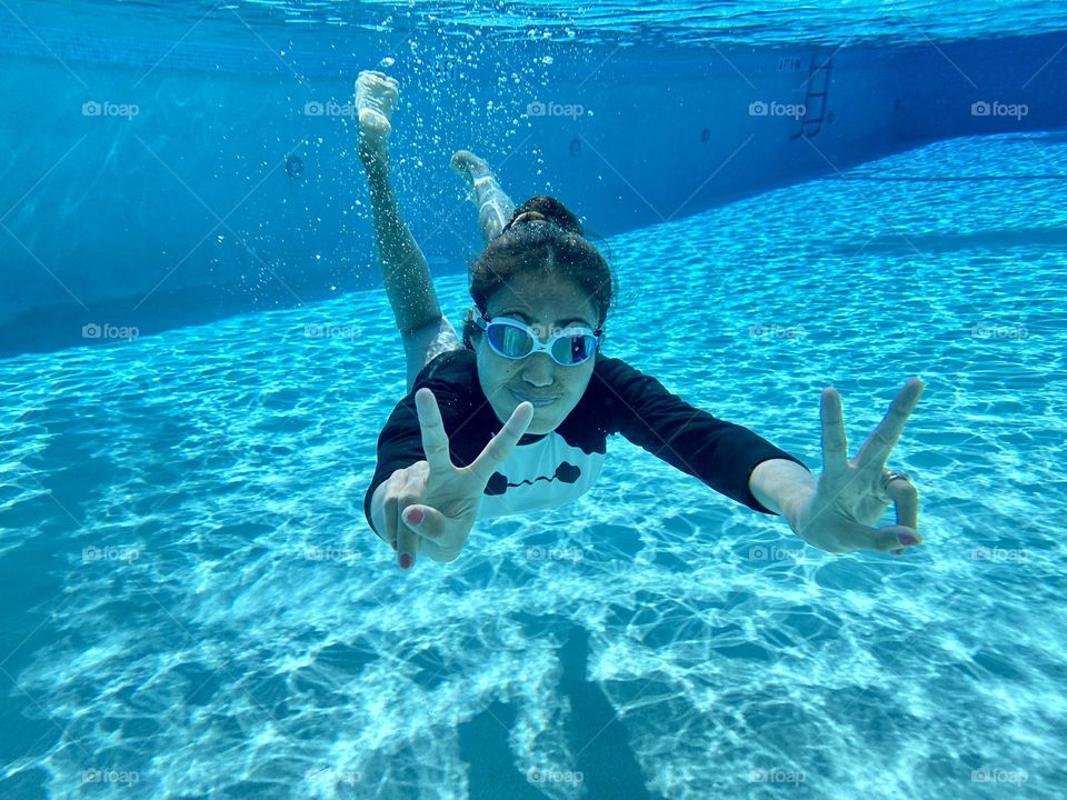 A woman making a sign of peace under the swimming pool. Pompano Florida USA. 